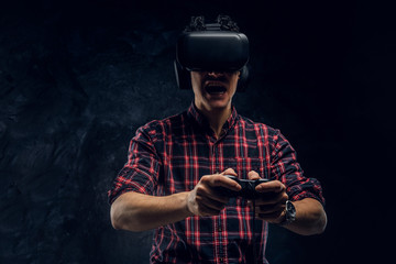 Teenager plays the game wearing virtual glasses and headphones on a black background in the studio