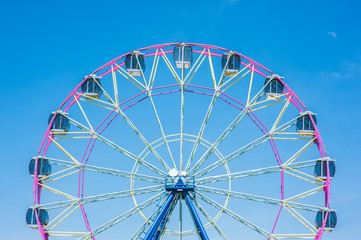 Ferris wheel in the summer morning on blue sky background