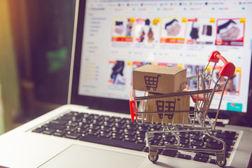 Shopping online concept - Parcel or Paper cartons with a shopping cart logo in a trolley on a...