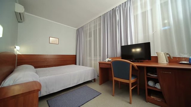 Hotel room with twin bed, tv, table. Window light