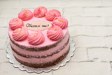 Pink cake with french macaroons from egg whites and a label 