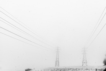 View of power line passing through snowy mist