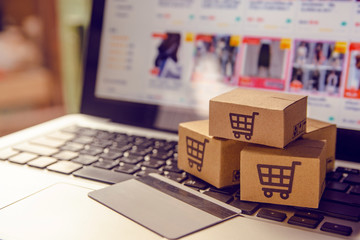 Shopping online. Cardboard box with a shopping cart logo in a trolley on a laptop keyboard payment by credit card and offers home delivery. - obrazy, fototapety, plakaty