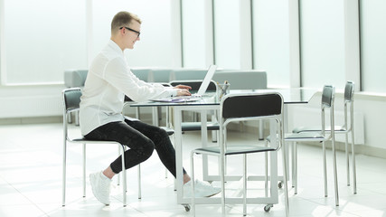 side view. young businessman typing on laptop