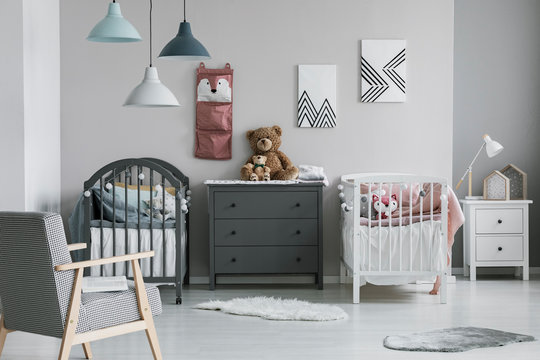 Pink Organizer On Wall Of Trendy Baby Bedroom With Two Cribs And Chest Of Drawers