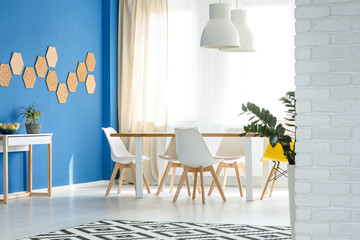 Elegant blue and white dining room with fashionable table and chairs in modern apartment