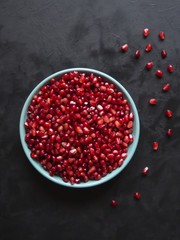 Pomegranate seeds on a plate on a black table. 