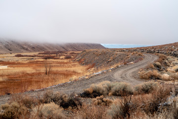 dirt roads in valley landscape with heavy cloudy mist layer obscuring the hills and mountains of the Sierra Nevada