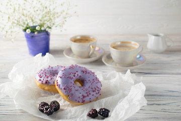 Freshly baked blackberry donuts with coffee and cream, morning breakfast setting