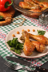 Chicken drumsticks baked in mustard marinade located on a plate against a dark background