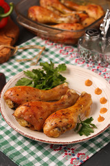 Chicken drumsticks baked in mustard marinade located on a plate against a dark background
