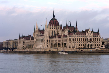 Fototapeta premium The building of the Hungarian Parliament on the banks of the Danube in Budapest is the main attraction of the Hungarian capital. Beautiful building against the gray sky.