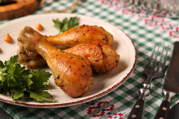 Chicken drumsticks baked in mustard marinade located on a plate against a dark background