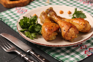 Chicken drumsticks baked in mustard marinade located on a plate against a dark background