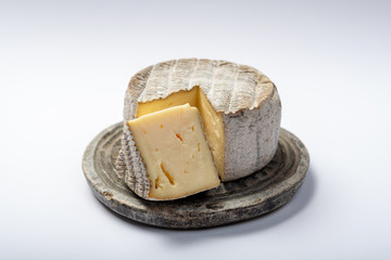 Round mature French Tomme cheese with cutted piece close up isolated