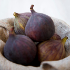 Fresh figs in a bowl on white wooden background, side view. Selective focus. Closeup.