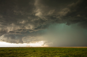 Fototapeta na wymiar A dangerous supercell storm containing torrential rain and large hail emits a green glow in the sky.