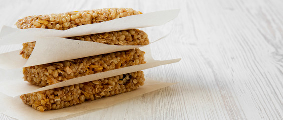 Granola bars on baking sheet over white wooden surface, side view. Copy space.