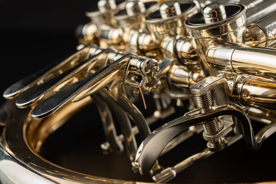French horn on a wooden table. Beautiful polished musical instrument.