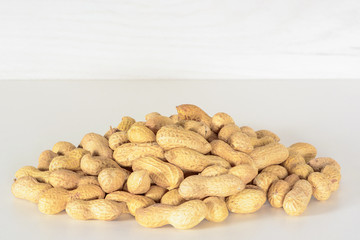 Peanuts. Small pile of peanuts on the white table and gray background. Peanut macro close up.