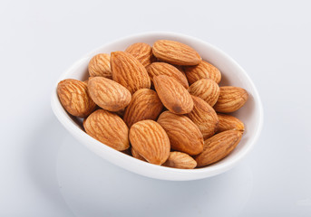 Pile of almonds in a small plate isolated on white background.