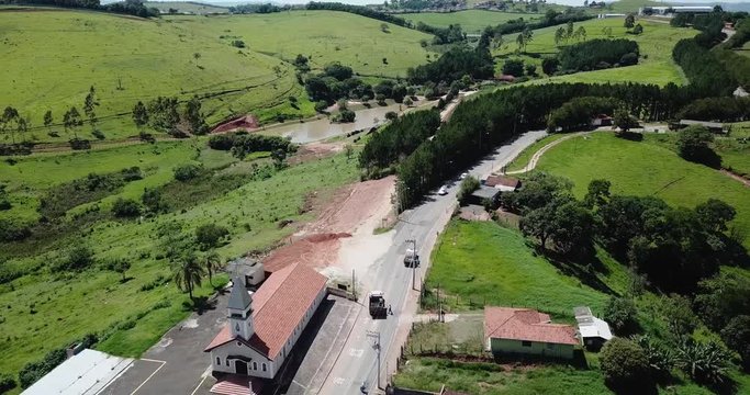 Aerial shot of a curved road with a little curch in the countryside