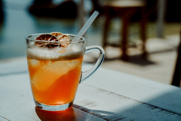 Cold ice tea with dried citrus fruits and cocktail straw tube in the glass
