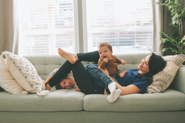 A mother and her two children having fun on the couch at home. 