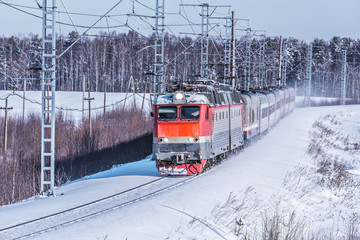 Passenger train approaches to the station at winter morning time.