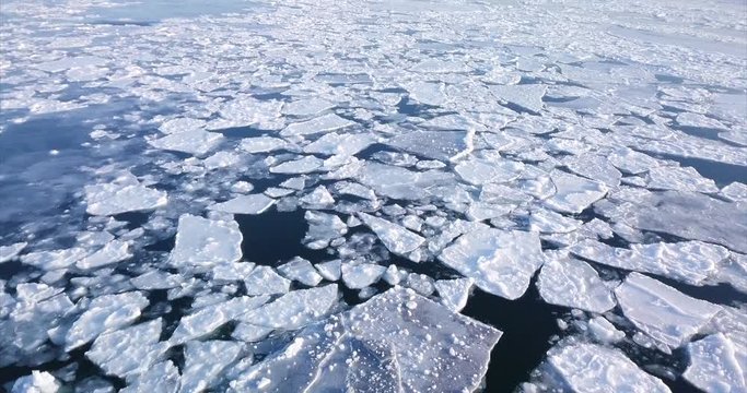 Flying above sea water with beautiful white ice floes. Aerial 