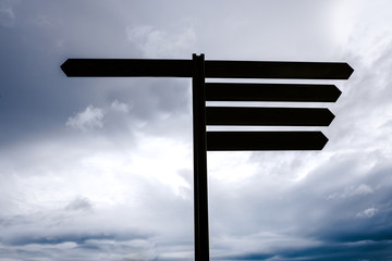 Blank sign pole, empty with space for text, with sky background with storm clouds, concept of doubt...