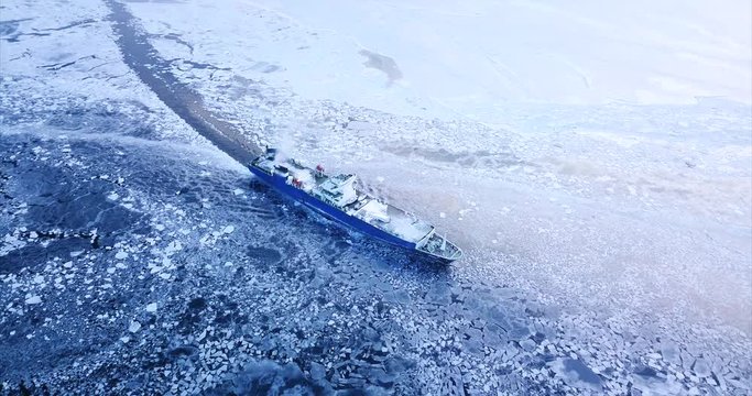 Aerial view of big ship floating through ice floes of winter Eastern Bosphorus strait. Vladivostok, Russia. Winter evening