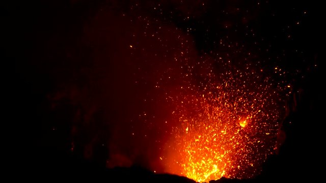 CLOSE UP: Hot flying magma and blazing flames illuminate the depths of Mount Yasur. Stunning shot of bright orange lava blasting out of the active volcanic crater on a remote island in the Pacific.