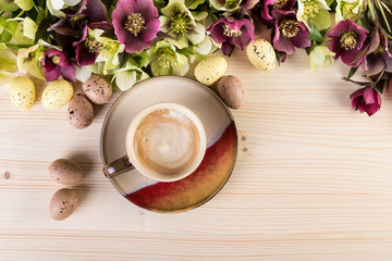 Coffee concept with spring flowers Easter eggs on light wood. Top view, copy space