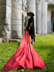 Femme agitant une étoffe de soie rouge dans les ruines d'un monastère moyen-âgeux.