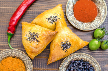 National Uzbek samsa dishes, tomatoes, red pepper and condiments on a brown wooden table