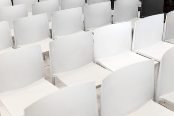 Many white chairs stand in several rows.
