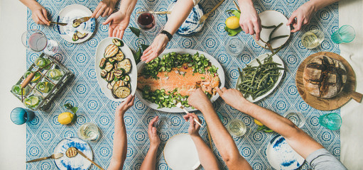 Mediterranean style dinner. Flat-lay of table with cooked salmon, starters, bread, lemonade over...
