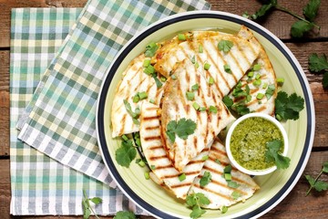 grilled quesadilla with green avocado, vegetable oil and cilantro sauce. Mexican traditional food, wheat tortillas. top view. copy space. vegan quesadilla