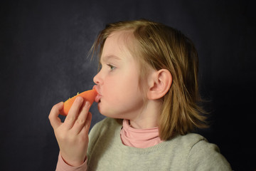 The child eats an orange. Girl with an orange. Portrait of a girl with fruit. Appetizing eating citrus.