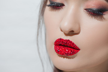 Obraz premium Stylish young brunette with bright and stylish makeup. Eye shadow with arrows and bright red lips