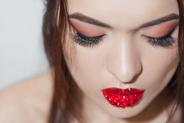 Stylish young brunette with bright and stylish makeup. Eye shadow with arrows and bright red lips