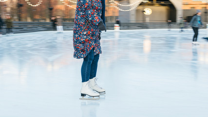 Cropped image of girl legs in white old fashioned skates riding in the rink, in motion/ outdoor ice rink, selective focus on female,  frozen lake, copy space/ winter, sport and leisure concept. 