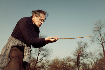 Man in ugly style dress practicing in dowsing with rods