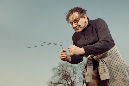 Man in ugly style dress practicing in dowsing with rods