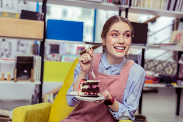 Impressed positive girl being shocked with taste of cake