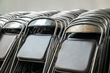 Old and Used Fold Rusty Metal Chairs Lay on the Wall.