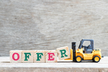 Toy forklift hold letter block R to complete word offer on wood background