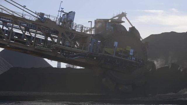 Coal terminal stacker reclaimer lifting coal pile slow motion