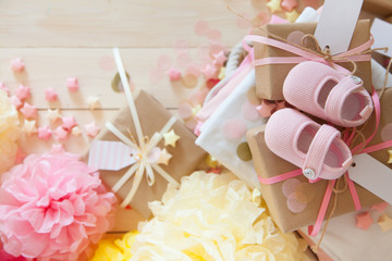 Gifts and pink decorations for girl baby shower indoors. close-up of baby shoes